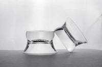 Two Oaxaca glasses on a gray counter with a white background. One glass is upside down and the other is tipped on its side resting on the other.