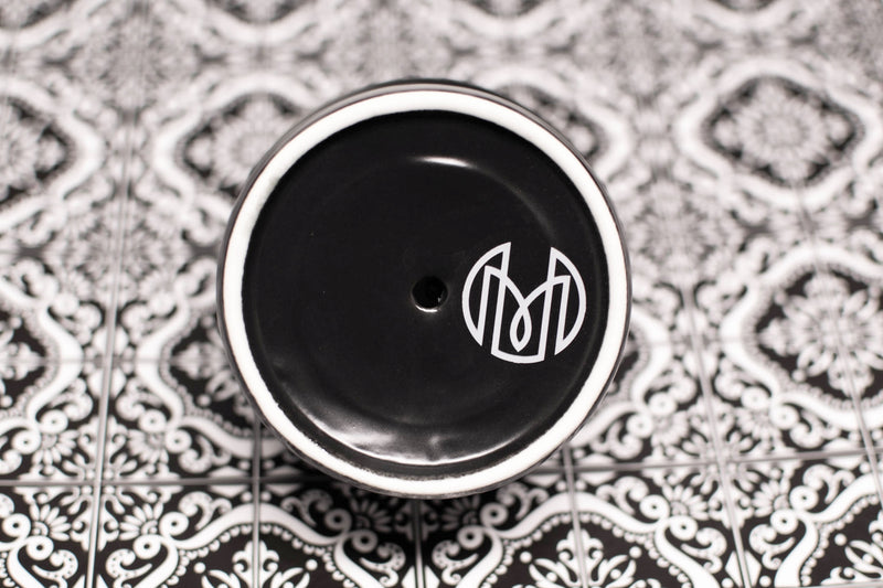 Bottom shot of the volcanic ash (black) Oaxaca glass showing the Historically Modern monogram, with an arabesque pattern tile in the background